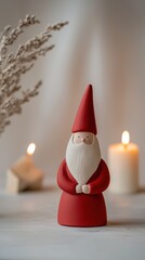 Fototapeta premium A minimalistic St. Nicholas Day decor features a charming red figure with a white beard surrounded by glowing candles and natural accents creating a warm festive ambiance