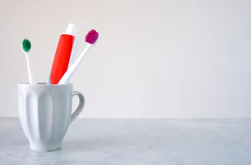 Colorful toothbrushes and toothpaste in a glass on the table