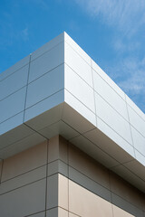 Obraz premium The exterior wall of a contemporary commercial-style building has aluminum metal composite panels and glass windows. The futuristic building has engineered diagonal cladding steel frame panels.