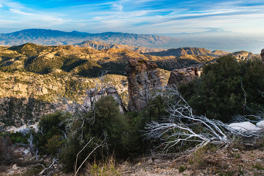 Granite cliffs with mountains and Tucson in the distance in late afternoon light as seen from high on Mount Lemmon in spring, Arizona