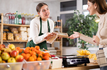 In store female employee offers girl customer to choose nougat, shows various dessert options, made from egg white, sugar, nuts and spices