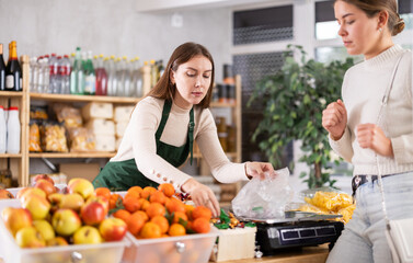 European saleswoman sells chocolates by weight and packs them in a bag. Seller weighs low-calorie candies on the scales. Buying natural delicious sweets.