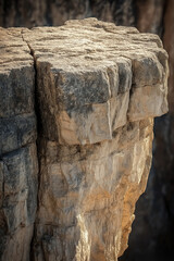 Stunning rock formation with sharp cliff edge overlooking vast canyon landscape during golden hour