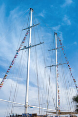 Majestic sailing ship masts with colorful flags against blue sky