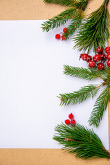 Festive preparation with evergreen branches and red berries on a blank sheet of paper during the holiday season