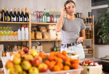 Young woman buyer forgot what she wanted to buy at grocery store