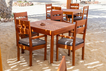 Cozy outdoor seating area in sunny beach environment with wooden table and chairs