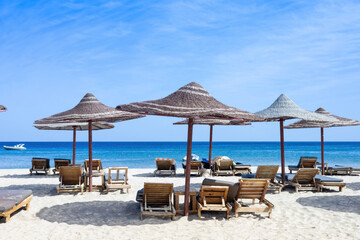 Tranquil beach scene with lounge chairs and straw umbrellas by the sea