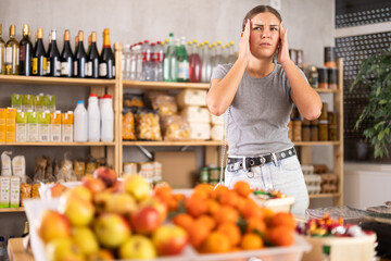 Female shopper suffers from headache while shopping at grocery supermarket