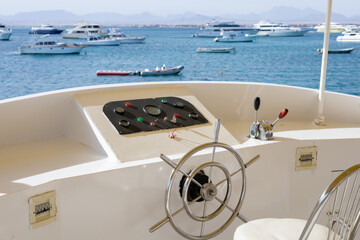 Obraz premium Scenic view of yacht wheel and boats in tranquil blue waters for boating enthusiasts