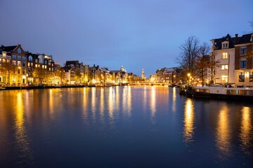 Canal in Amsterdam with illuminated buildings and reflection on the water