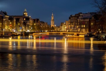 Obraz premium Canal in Amsterdam with illuminated buildings and reflection on the water