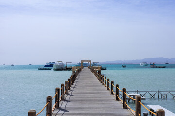 Fototapeta premium Serene pier overlooking turquoise sea with boats on a clear day