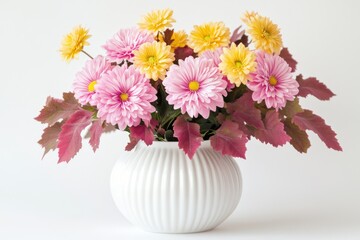 Pink and yellow chrysanthemum bouquet in a white vase with red leaves.