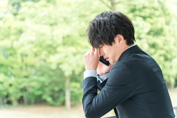 スマホ・スマートフォンで通話しながら悩むアジア人ビジネスマン・新入社員
