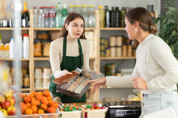 Saleswoman in a supermarket offers various sweets to the buyer near the counter. Buyer chooses natural low-calorie desserts.