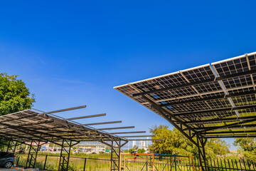 Obraz premium Solar panel carport providing shade for parked vehicles on a sunny day. Renewable energy infrastructure combining solar power generation and parking solutions for sustainable development.