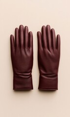Obraz premium A pair of burgundy leather gloves laid flat on a neutral background.