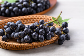 Black grapes in basket on white table, Seedless grapes