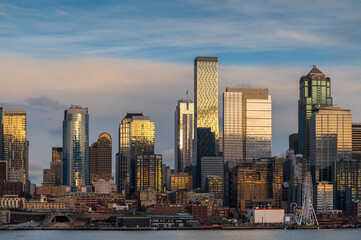 Obraz premium Seattle Skyline as seen from Elliott Bay with no viaduct during a lovely and colorful sunset. Modern skyscrapers, ferris wheel, and a newly renovated waterfront make a beautiful view from the water.