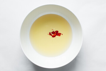 overhead view of oil and red food color being mixed in a white mixing bowl, process of making red velvet cake