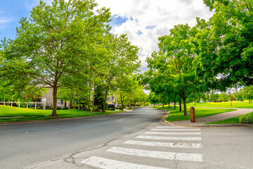 A shady tree lined street in a subdivision of homes across from a park in the suburban city of Coeur d'Alene, Idaho USA.	