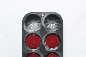 overhead view of Red velvet cupcake batter in a fluted cupcake pan, top view of Red velvet cupcake batter in a fluted muffin pan, process of making valentines cupcakes or muffins