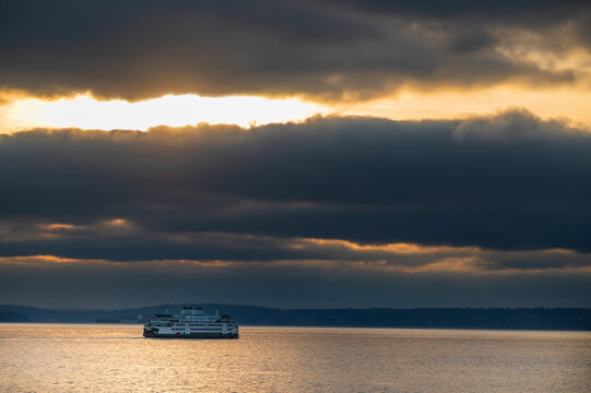 Dramatic clouds frame a ferry boat sailing across Elliott Bay from Seattle towards Bainbridge Island. Rain clouds are the norm for this part of the Pacific Northwest area of Puget Sound.