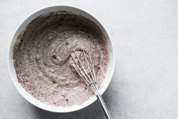 Overhead view of red velvet cake batter being mixed in a white ceramic bowl, Red velvet cake batter in white ceramic mixing bowl, process of making red velvet cake