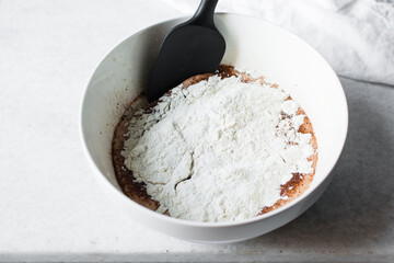 Overhead view of flour being added to madeleine batter, mixing flour into batter, process of making...