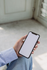Mock up smartphone of hand holding black mobile phone with blank white screen