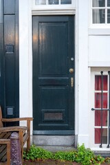 The facade of the house with chair and green front door in Amsterdam, Netherlands