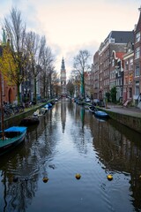 Naklejka premium Cityscapes of Amsterdam with boats moored along the canal with Zuiderkerk (Southern Church) view