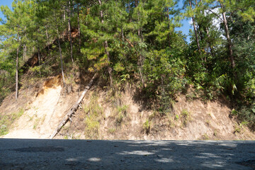 Fototapeta premium Horizontal view of asphalt road under the shade. background is a mountain ridge covered with trees. At Rak Chang Viewpoint, Pai, Mae Hong Son, Thailand.