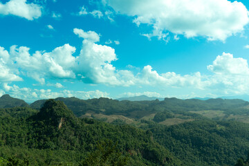 landscape of rolling green hills and valleys under a bright blue sky with scattered white clouds. Landmark hills of village Ban Jabo. Mae Hong Son of Thailand.