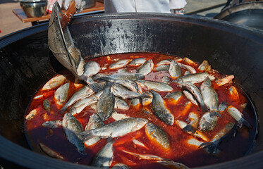 Freshly caught wild fish soup cooked in an outdoor wood-fired iron pot