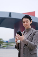 Fototapeta premium Modern Businesswoman Engaged with Smartphone in Urban Setting