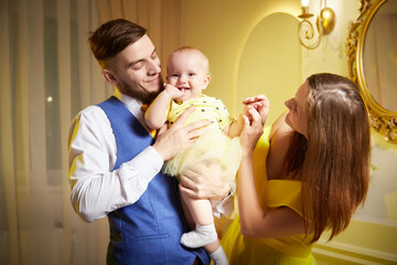 Family portrait with a young girl in a yellow dress in a decorated room with floral arrangements