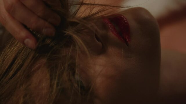 Extreme close up of a beautiful young woman seductively putting her hair in front of her face in slow motion