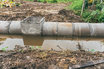 Large water pipes are laid in ditches for drainage system installation,supported by excavators.This...