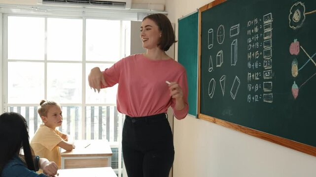 Caucasian teacher request student to raise hand up to answer question at in front of classroom. Attractive instructor calling children for writing answer in math lesson at elementary school. Pedagogy.
