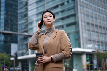 Confident Businesswoman in Urban Setting with Coffee and Smartphone