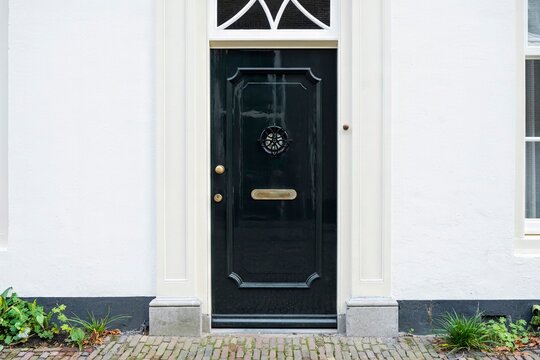 The facade of the house with glass of windows and black front door in Amsterdam, Netherlands