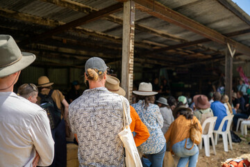 group of farmers at a field day learning about farm community  wearing a hat being sun smart. studying crops in a field, studying a soil and animals