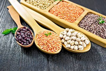 Lentils red with chickpeas and beans in spoons on dark board