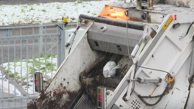 Rear loading waste collection garbage truck with bin tipper. Bin tipper mechanically lifts and inverts garbage bins in winter.