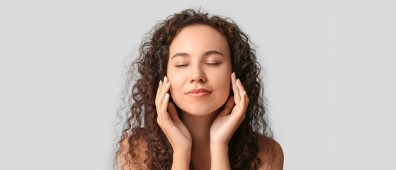 Beautiful young African-American woman with healthy moisturized skin on white background