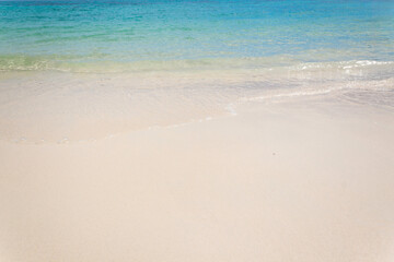 Clean ocean waves on white sand beach with turquoise emerald coloured water. Nature seascape background.