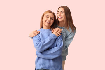 Happy young woman hugging her mother on pink background. International Hug Day