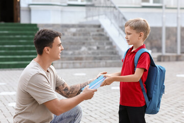 Obraz premium Father giving books to his little son near school